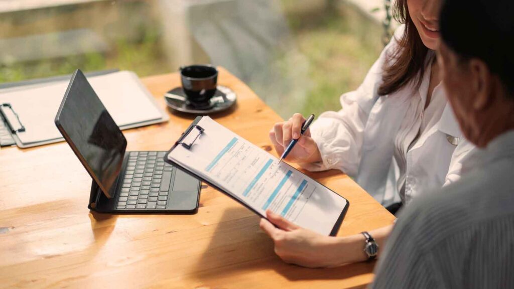 A business broker reviewing pre-sale documents with a client, ensuring accurate financial preparation for a successful transaction. Business Broker Pre-Sale Prep.